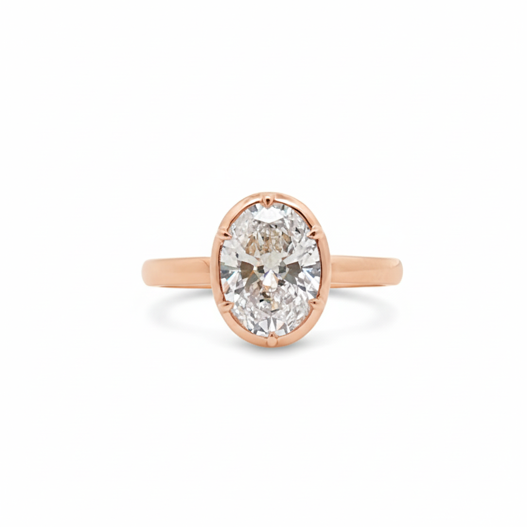 alt="front view of lab grown oval cut diamond bezel set engagement ring in 14K rose gold"