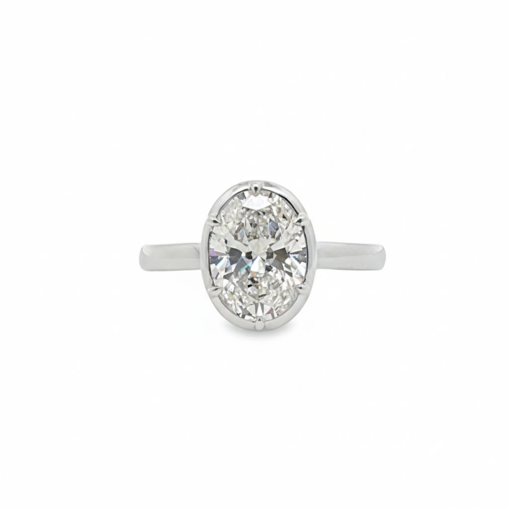 alt="front view of lab grown oval cut diamond bezel set engagement ring in 14K white gold"