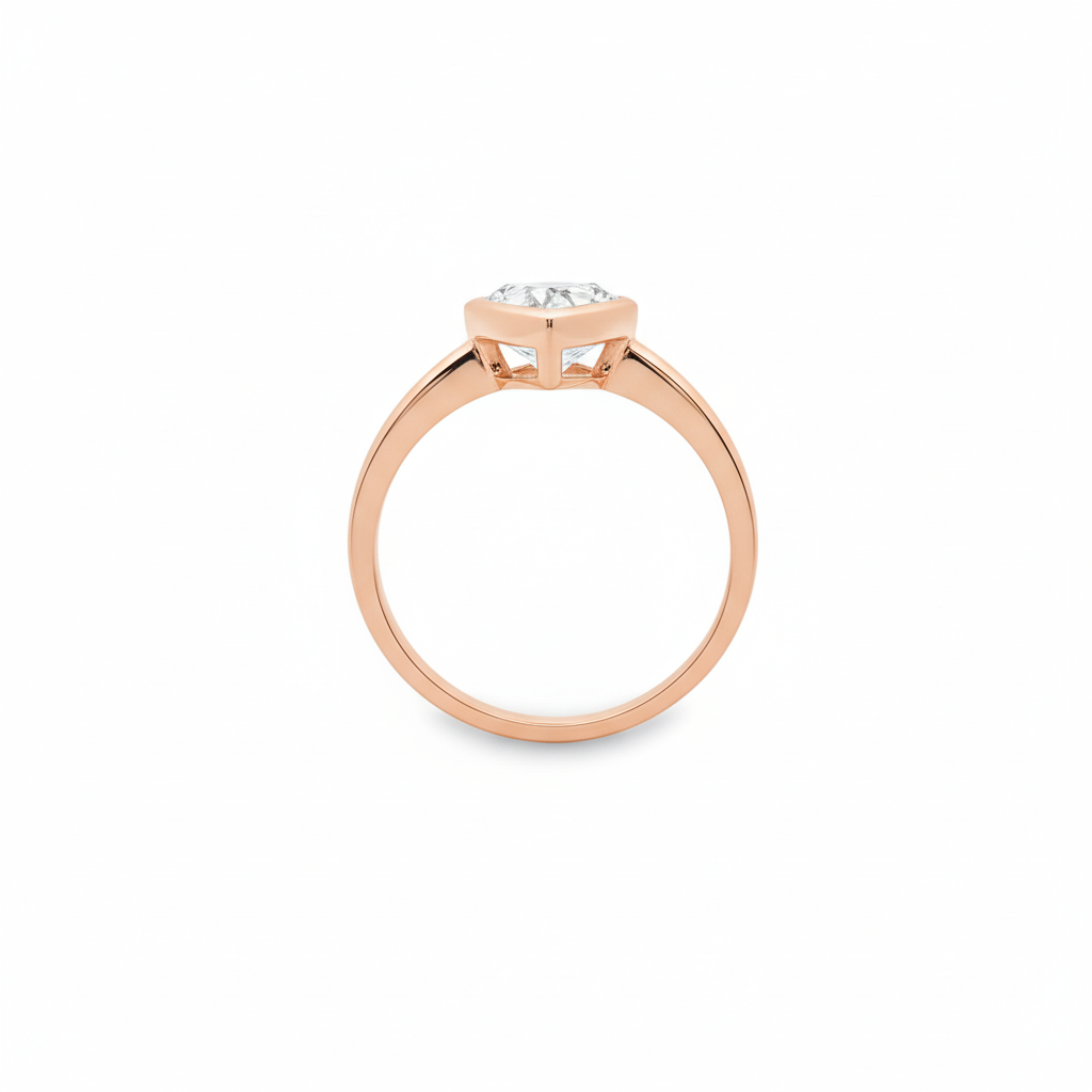 alt="profile view of lab grown pear cut diamond bezel set engagement ring in 14K rose gold"