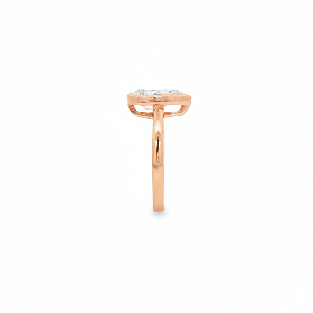 alt="side view of lab grown pear cut diamond bezel set engagement ring in 14K rose gold"