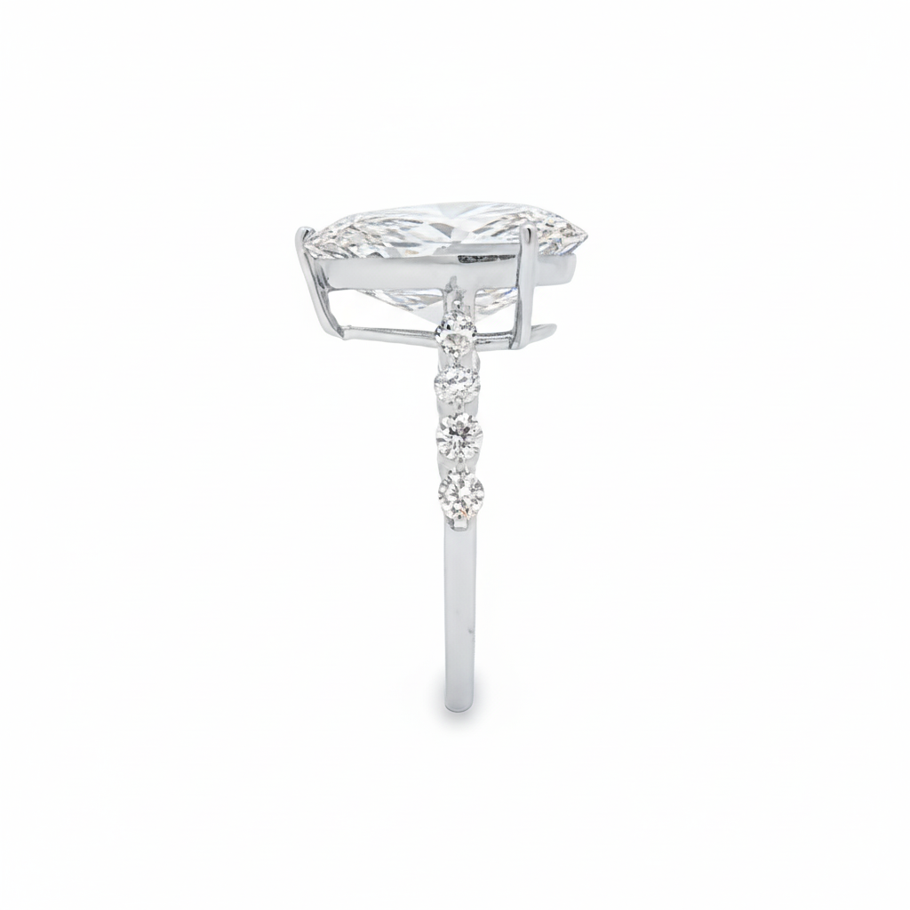 alt="side view of lab grown pear cut diamond engagement ring with accent band in 14K white gold"