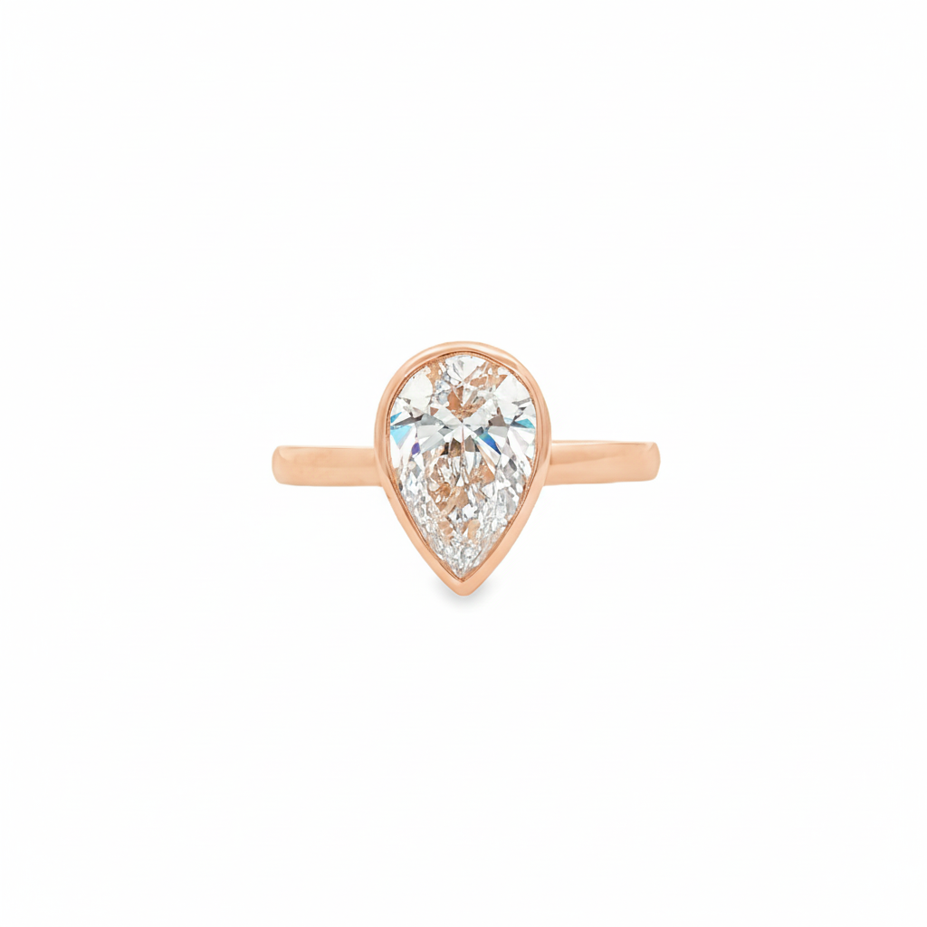 alt="front view of lab grown pear cut diamond bezel set engagement ring in 14K rose gold"