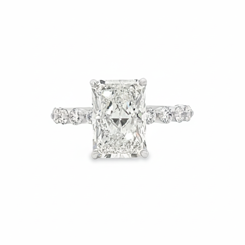 alt="front view of lab grown radiant cut diamond engagement ring with accented band and hidden halo in 14K white gold"