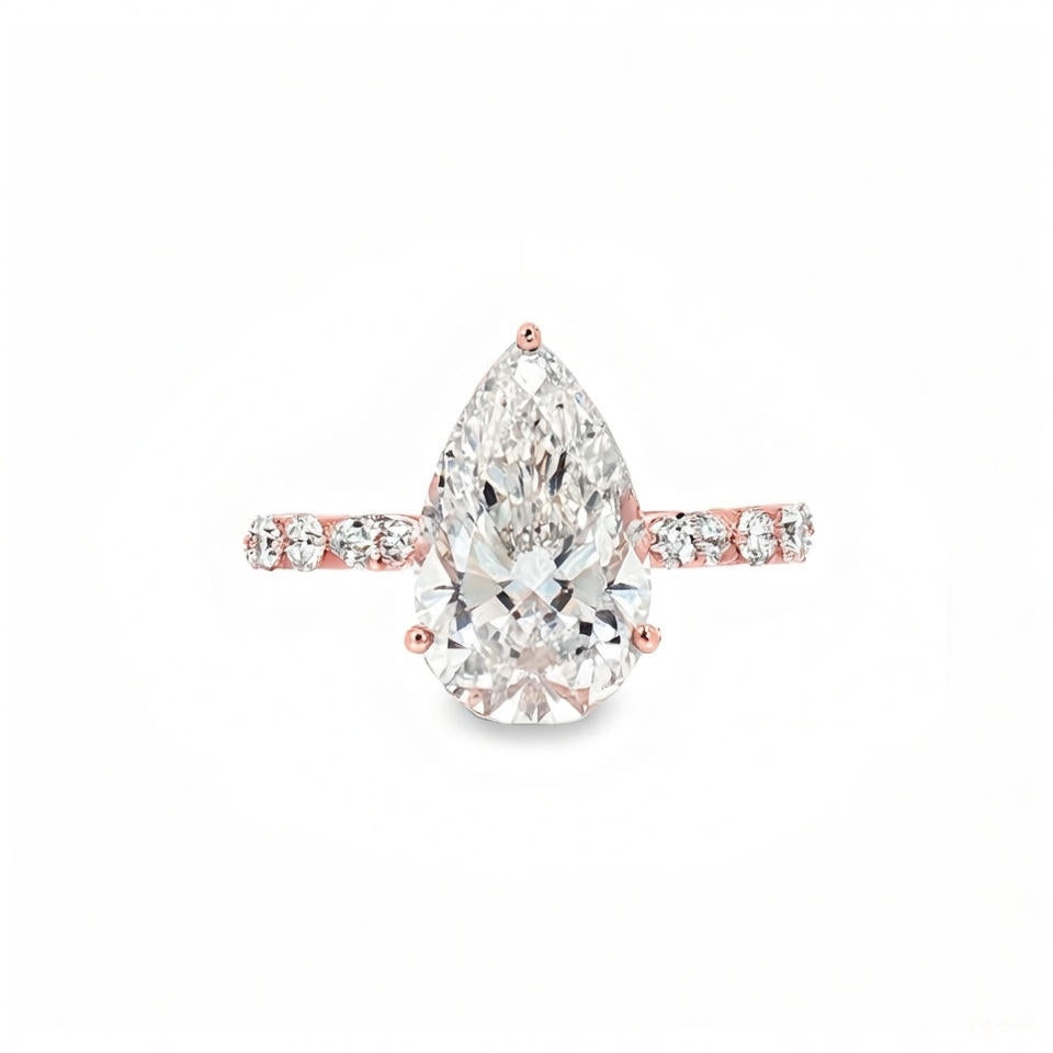 alt="front view of lab grown pear cut diamond engagement ring with accent band in 14K rose gold"