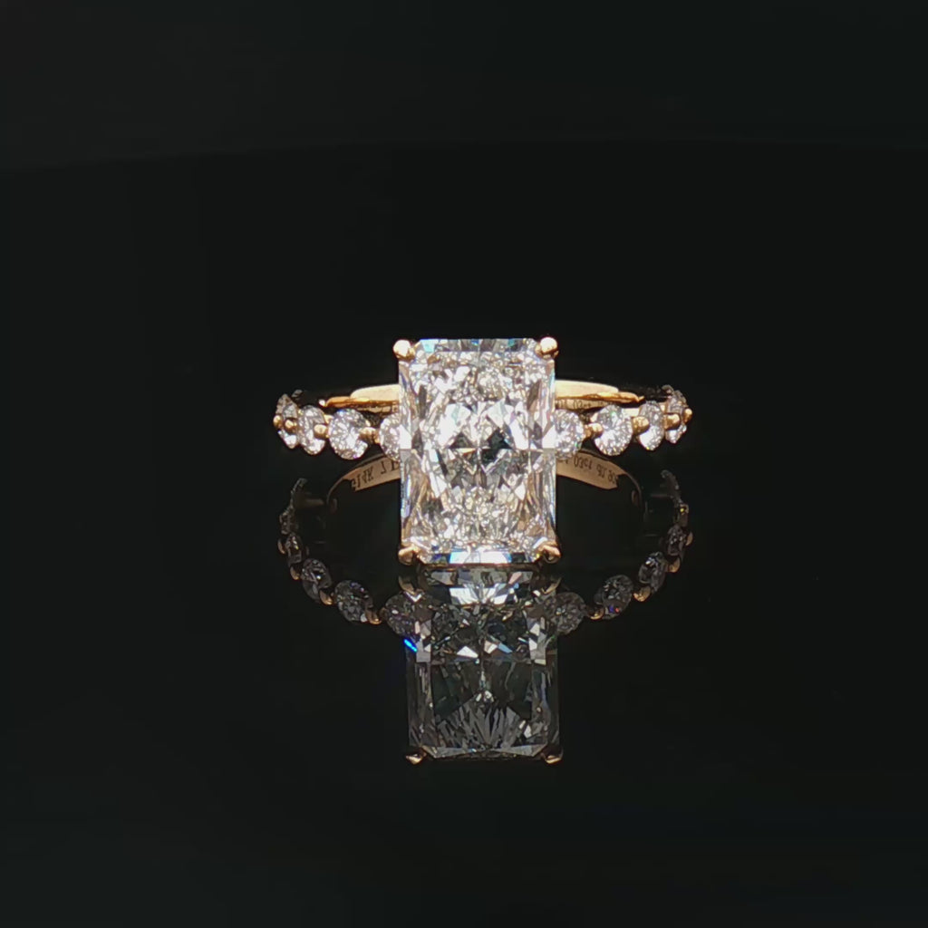 alt="360 video of lab grown radiant cut diamond engagement ring with accented band and hidden halo in 14K yellow gold"
