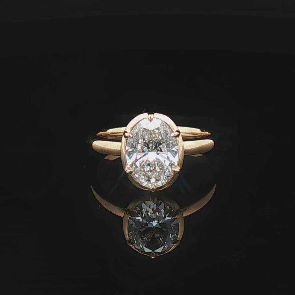 alt="360 video of lab grown oval cut diamond bezel set engagement ring in 14K yellow gold"