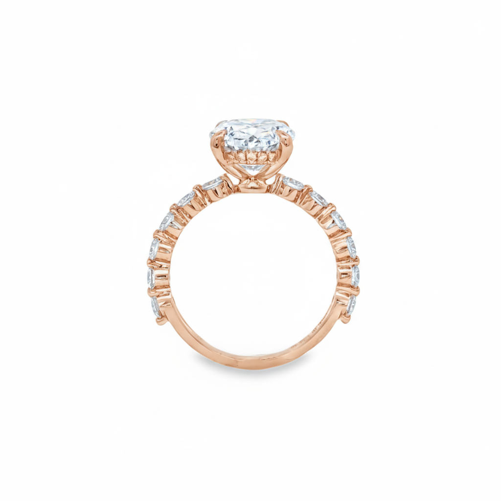 alt="profile view of lab grown oval cut diamond engagement ring with accented band in 14K rose gold"